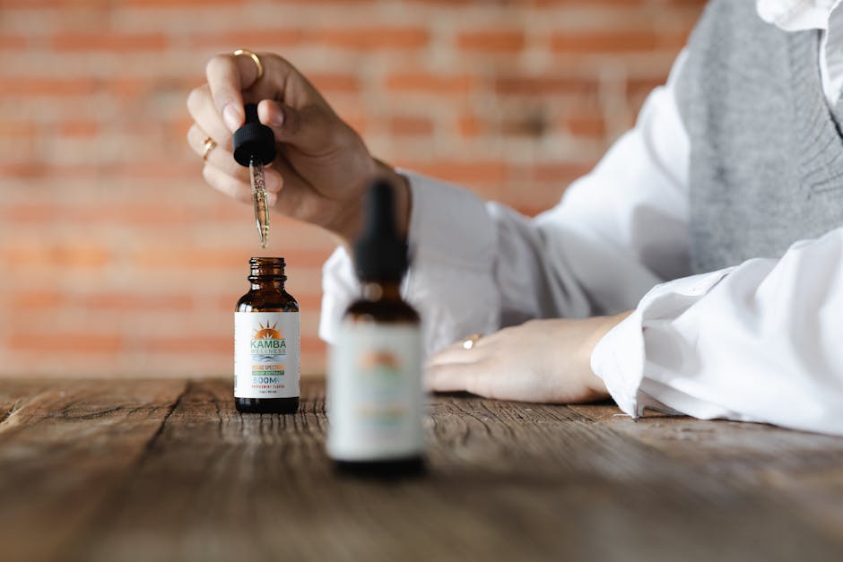 Close-up of CBD oil dropper with bottle on wooden table, brick wall background.