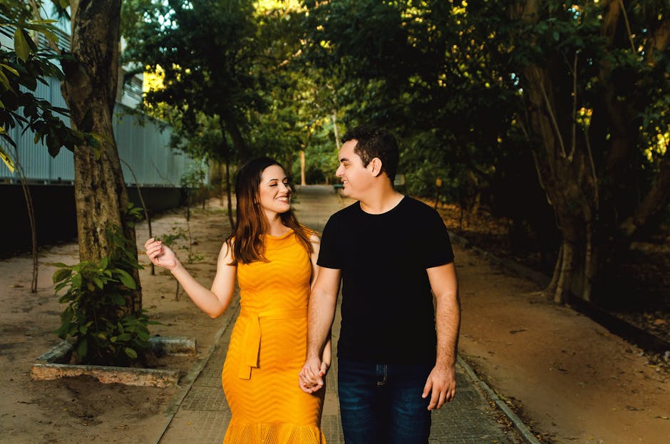 Couple walking hand in hand in a sunlit park, smiling and enjoying each other's company.