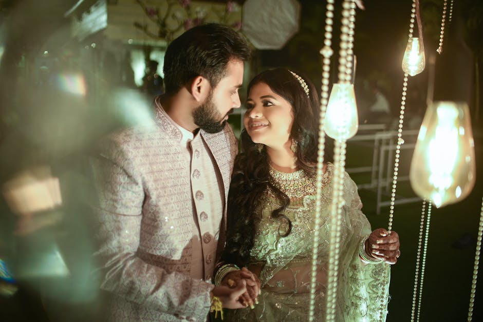 Smiling couple embracing under warm lights during a festive evening celebration.