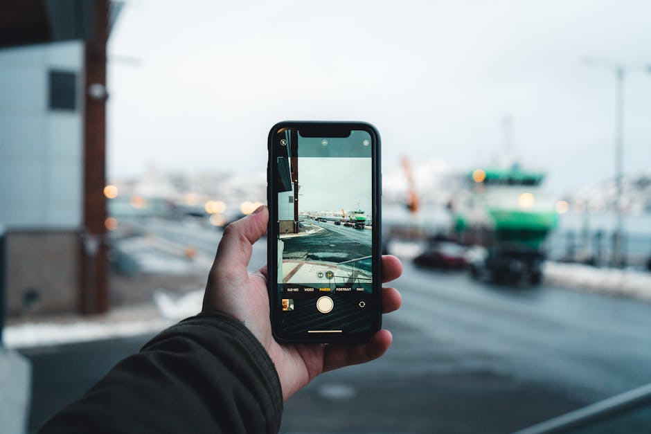 Person captures an urban winter scene on a smartphone, focusing on the street view ahead.