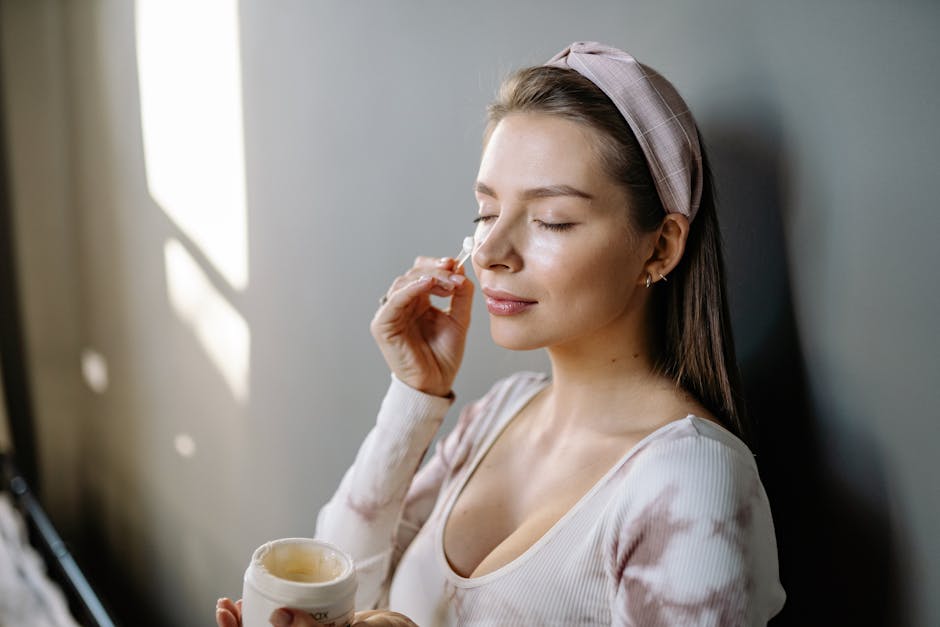 A woman with eyes closed applying skincare cream to her face, emphasizing self-care.