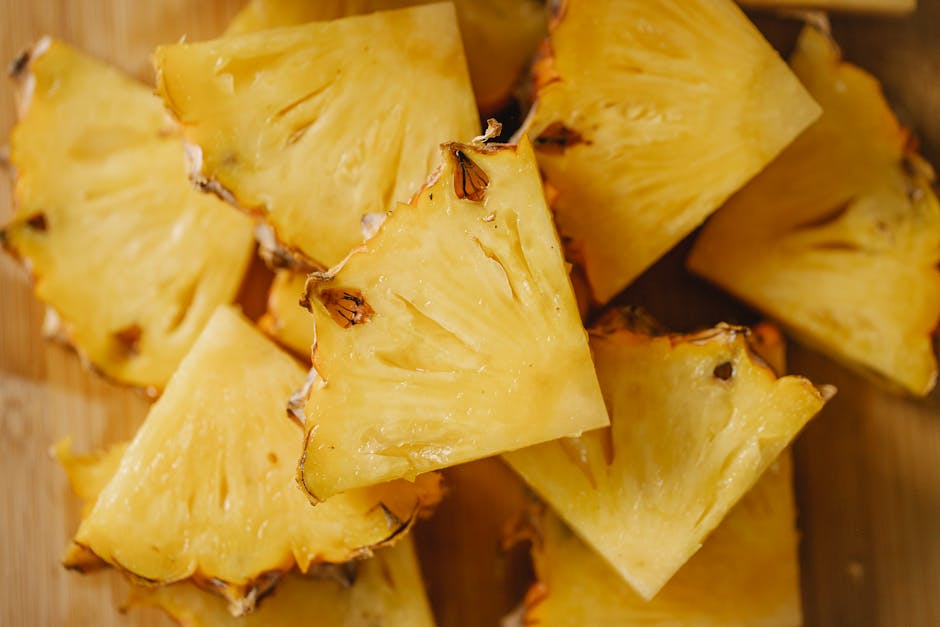 Overhead view of juicy pineapple slices on a wooden board, showcasing vibrant yellow color and natural texture.