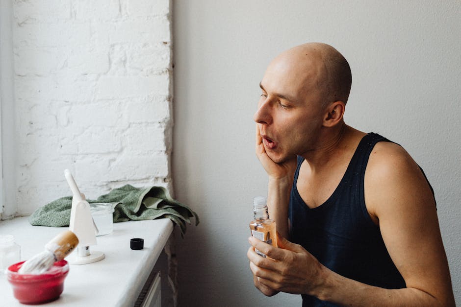Adult man applying aftershave lotion in a bright bathroom, focusing on skincare routine.