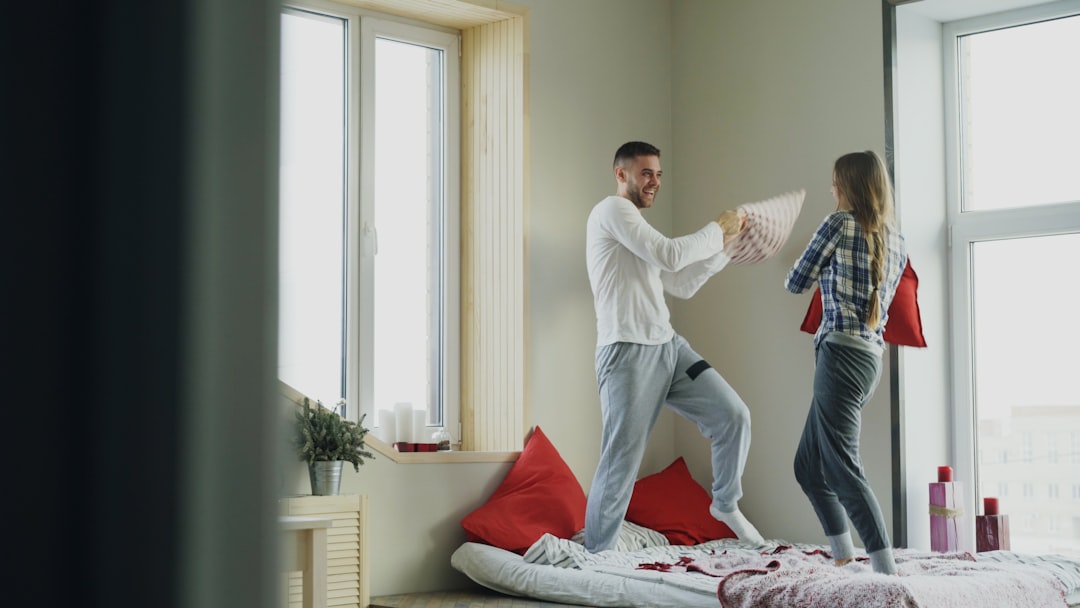 Couple having a playful pillow fight in bed.