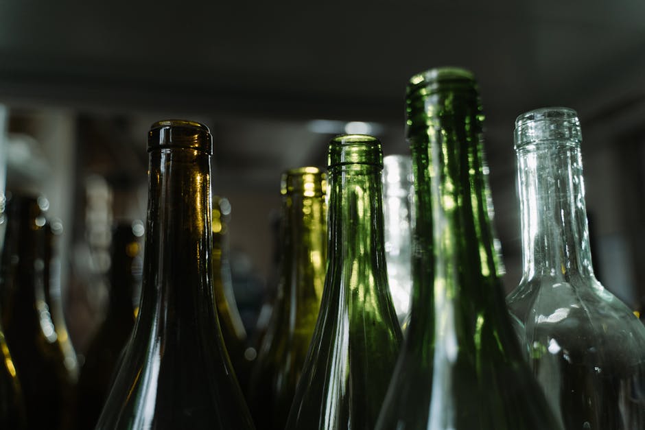 A moody still life of green and clear glass bottles captured in low light, showcasing recycling and eco-friendly themes.