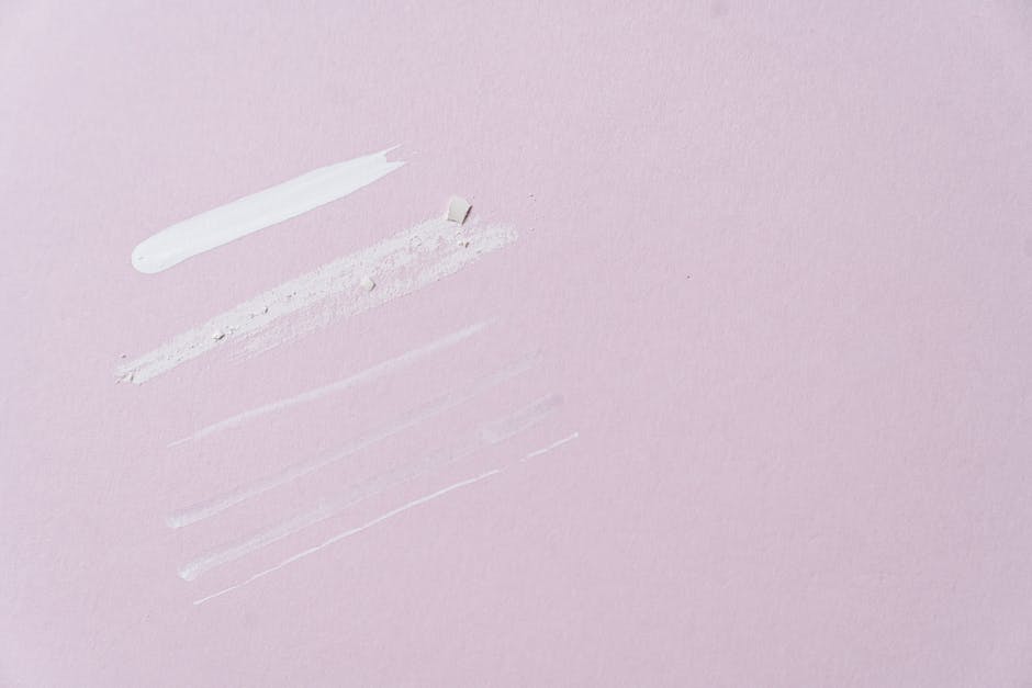 Flat lay of skincare product swatches on a pastel pink background, ideal for beauty and cosmetics themes.
