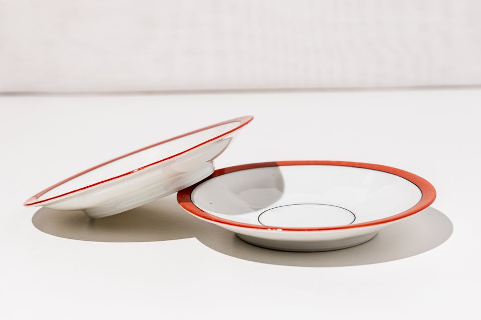 Simple white ceramic bowls with red rims, perfect for modern dining settings.