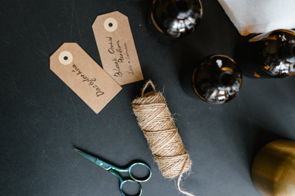 Flat lay of essential oils, twine, scissors, and organic labels for aromatherapy products.