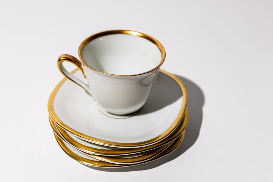 A minimalist white ceramic teacup with elegant gold trim set against a white background.