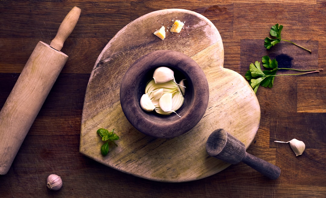 Garlic and pestle arranged on a wooden board.