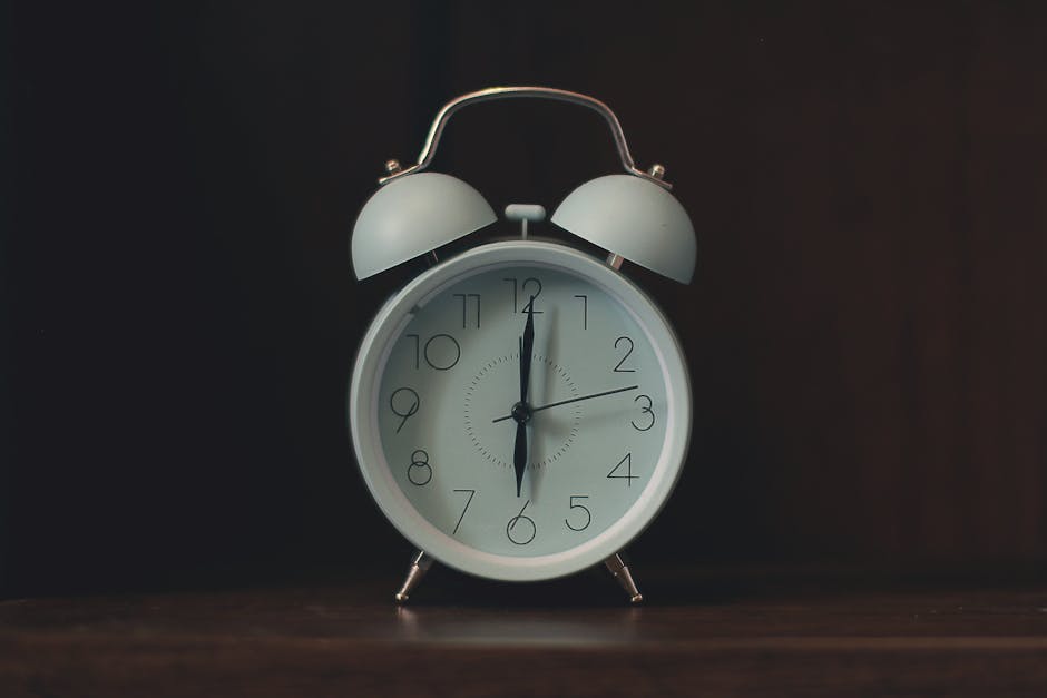 Close-up of a classic white vintage alarm clock on a wooden surface.
